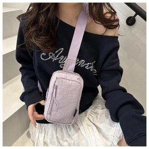 Lifestyle shot of light purple nylon sling bag worn by a model on white stairs