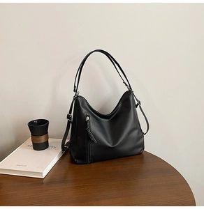 Detail shot of a black matte hobo bag with zipper on a wooden table setup