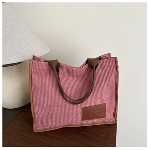 Detail of pink corduroy tote bag showing ribbed texture and brown leather logo patch