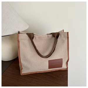 Detail of beige corduroy tote bag showing ribbed texture and brown FASHION BAG leather patch