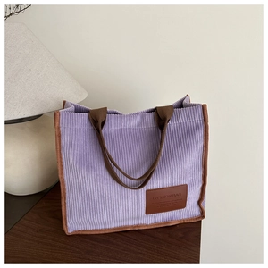 Detail of purple corduroy tote bag with brown straps and embossed fashion leather patch