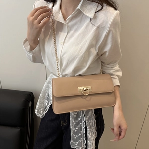 Beige matte leather crossbody bag with gold chain strap shown on model in minimalist room