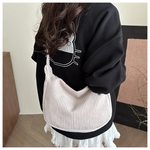 Detail of beige corduroy dumpling bag with soft vertical texture on female model