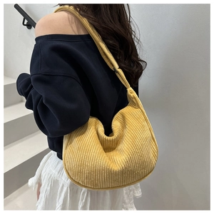 Detail of yellow corduroy crescent bag showing wide ribbed texture and half-moon shape