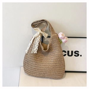 Détail du sac hobo en paille tressée avec un nœud en dentelle blanche et texture tissée