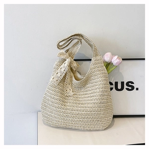 Détail d'un sac cabas en paille avec un nœud en dentelle délicat et une texture tressée