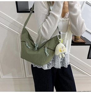 Detail of army green nylon hobo bag with multiple zipper pockets and plush charm