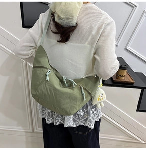 Detailed back view of green crescent crossbody bag with white plush smiley charm