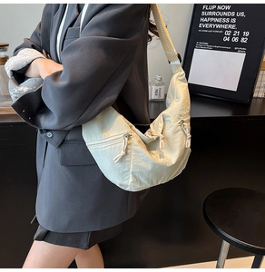 Detail of off-white crescent crossbody bag featuring nylon texture and functional zippers