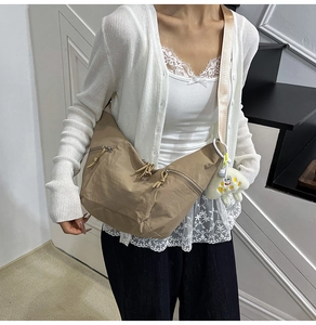 Detail of khaki crescent crossbody bag with zipper pockets and wide fabric strap