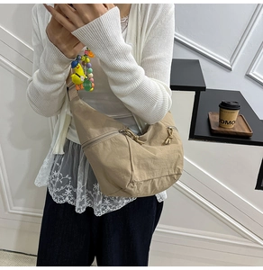 Detail of khaki nylon crescent bag with cute duck charm and LOVE beaded keychain