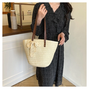 Detail of hand-woven straw tote with leather handles and a delicate lace bow accent