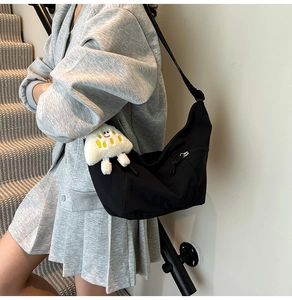 Detail of minimalist black crescent bag featuring a soft white cloud charm accessory