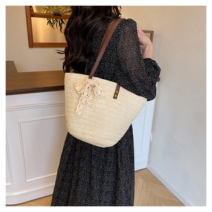 Detail of beige straw tote bag with delicate lace bow and brown faux leather straps