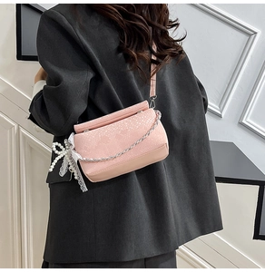 Detail of pink faux snakeskin bag with silver chain and lace pearl bow accessory