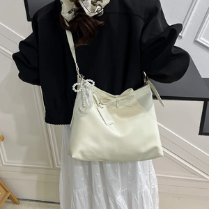 Sac fourre-tout chic en cuir crème avec nœud et pendentif perle sur mannequin