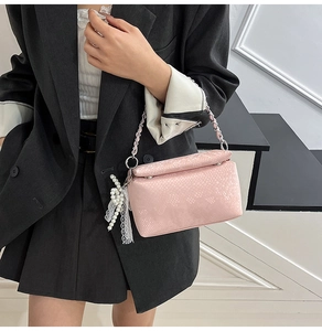 Detail of pink snake-pattern shoulder bag with silver chain and pearl bow accessory