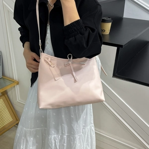 Sac à bandoulière rose avec nœud porté par un mannequin dans un style décontracté