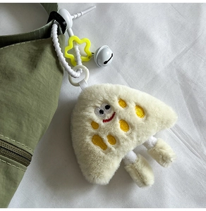 Detail shot of a plush cheese charm with embroidery, small bell, and star ring attachment