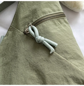 Close-up of olive green nylon bag with metallic zipper and braided cord pull detail