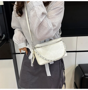 White snakeskin embossed crossbody bag with silver chain and pearl lace bow detail on model