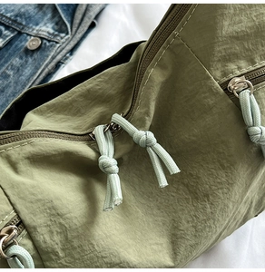 Detail of army green nylon fabric with metal zippers and woven rope pullers