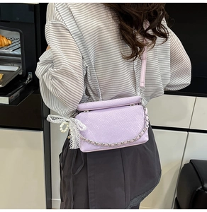 Close-up of light purple square crossbody bag with snake pattern and lace bow detail