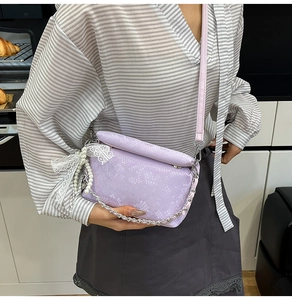 Detail of lavender box bag with scale texture and lace pearl bow accessory on shoulder