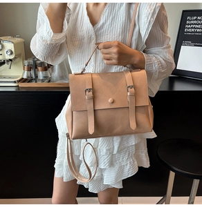 Detail of nude pink vintage messenger bag held by woman in a stylish cafe setting