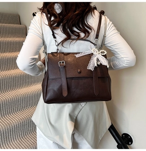 Detail view of dark brown vintage backpack with lace bow and pearl charm on a model