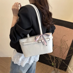 Minimalist white leather tote bag with silk bow detail worn by model on shoulder
