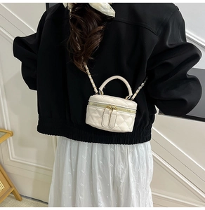 Nahaufnahme einer Mini-Stepptasche in Beige mit goldener Kette an einem Model