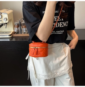 Detail einer orangefarbenen gesteppten Mini-Tasche mit Lederkettenriemen am Modell