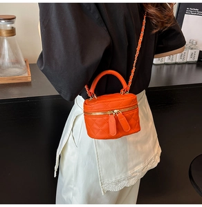 Detailansicht einer gesteppten orangen Mini-Vanity-Case-Tasche mit Kettenriemen als Umhängetasche