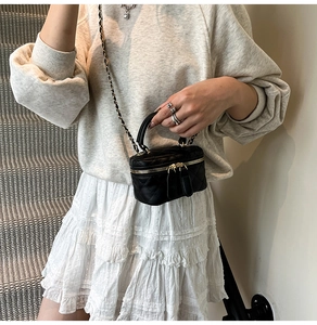 Detail einer schwarzen Mini-Stepptasche mit goldener Kette und Griff am Modell