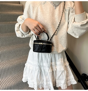 Detail der gesteppten Mini-Tasche mit zwei Gold-Reißverschlüssen und Kettenriemen