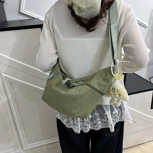 Olive green nylon crescent crossbody bag with multi-pocket design and cute plush charm