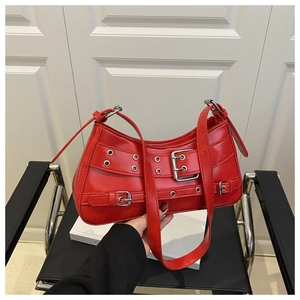 Macro detail of red faux leather shoulder bag with metallic eyelets and belt buckles