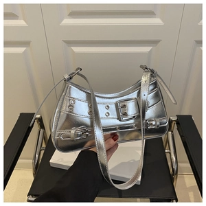 Detailed view of silver metallic shoulder bag featuring buckle straps and chrome eyelets