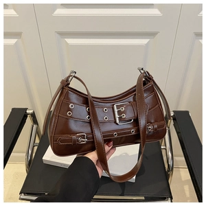 Detail of dark brown leather shoulder bag with wide belt buckle and metal eyelets decoration