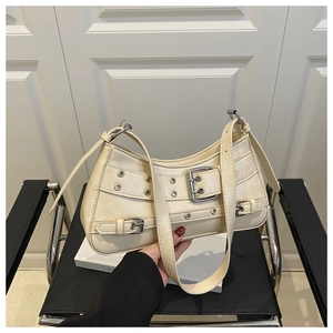 Close-up of cream shoulder bag with metallic buckle details and silver eyelets on leather
