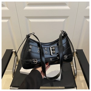 Detail of black crescent shoulder bag featuring silver metal eyelets and belt buckle straps