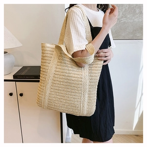 Detailed view of woven straw tote bag texture and fringe tassel in a lifestyle setting