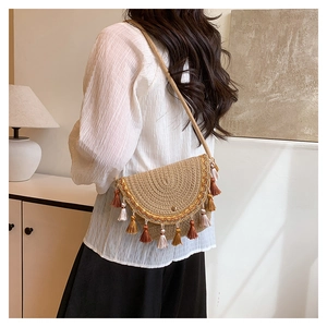Detail of woven straw crossbody bag with colorful tassels and thin shoulder strap