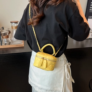 Gelbe Mini-Umhängetasche mit Rautenmuster und Goldkette in einem Lifestyle-Café-Ambiente