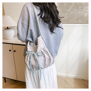 Détail du sac floral avec fermeture à cordon et ruban à carreaux bleu sur la bandoulière