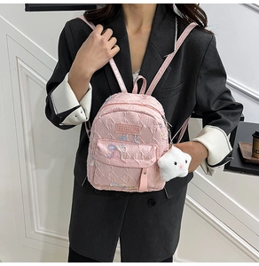 Detail of pink quilted mini backpack with embroidered bows and plush cloud charm