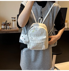 Detail of white quilted mini backpack with butterfly embroidery and cloud pendant