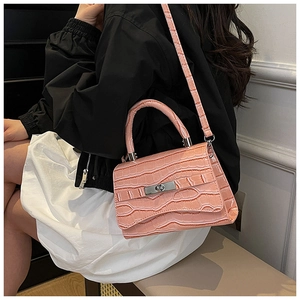 Detailed close-up of pink faux leather bag with crocodile texture and metal lock buckle