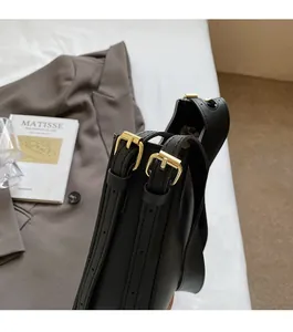 Detail of premium gold-tone metal buckles on a black leather bucket bag shoulder strap